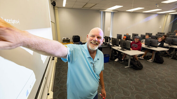 Keith Paschal gives a smile as he points to the screen at the front of his classroom.