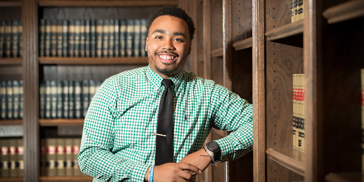 MSU Student Brandon Hill stands in private library with legal texts