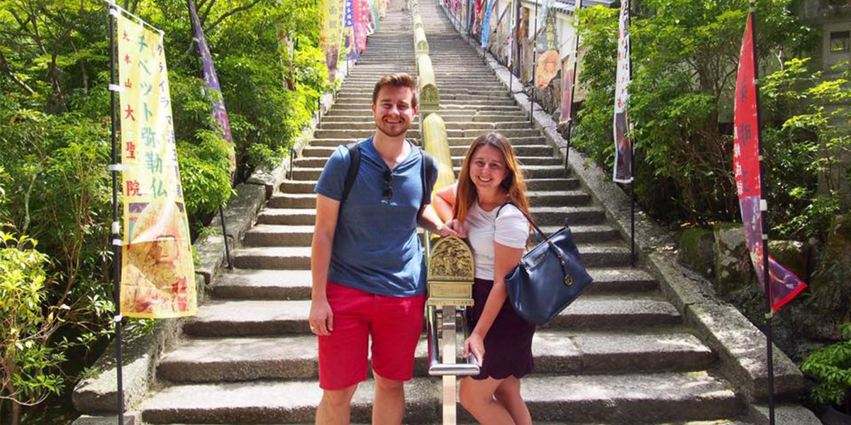 Doctor Marijana and her husband stand at the foot of Japanese shrine's outdoors footsteps