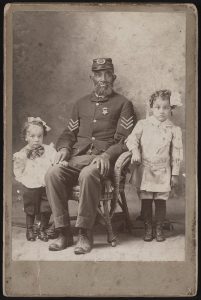 Portrait of an unidentified African American Civil War veteran in a Grand Army of the Republic uniform with two children