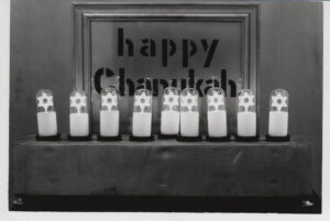 Nine candles in front of a sign that reads "happy Chanukah"