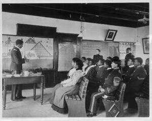 Photo of male and female African American and Indian students in a classroom in Hampton, VA in 1899.