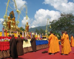 Vesak celebration with monks praying before a statue of Buddha