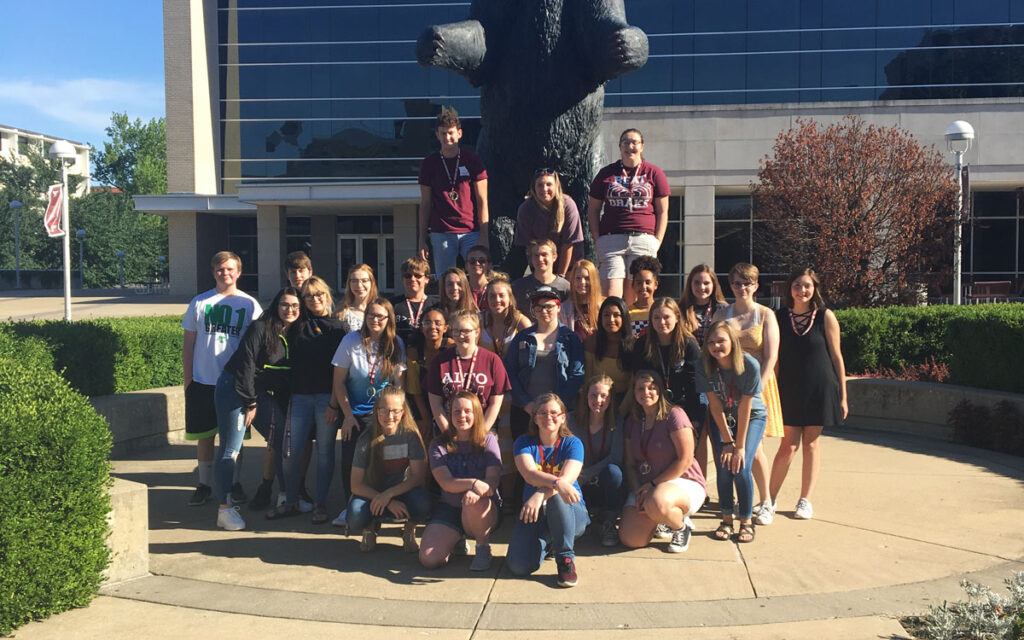Bear Partnership group posing in front of Bear statue