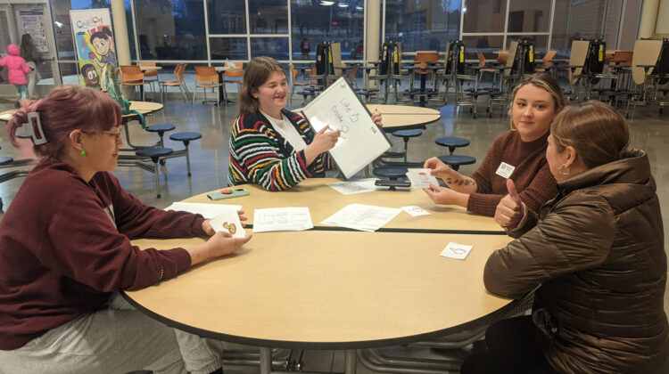 MSU students teach an ELL around a table.