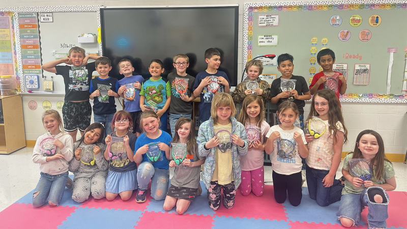Students smile and each hold a pair of headphones