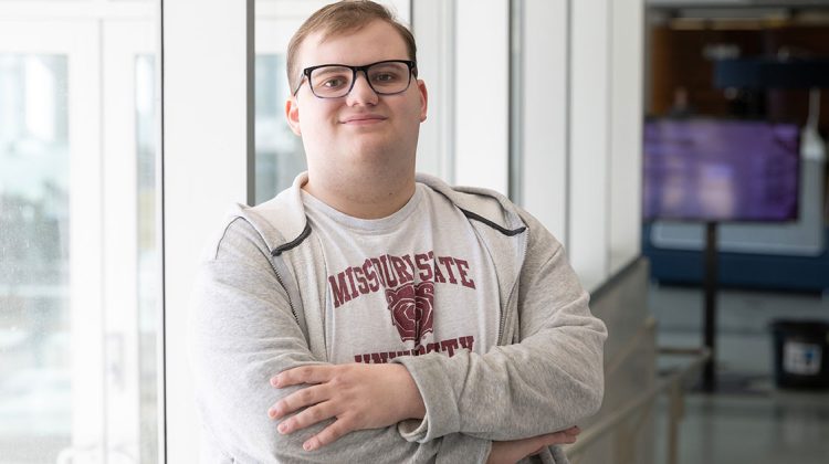 Daniel Paige crosses his arms to pose for a picture in Meyer Library.