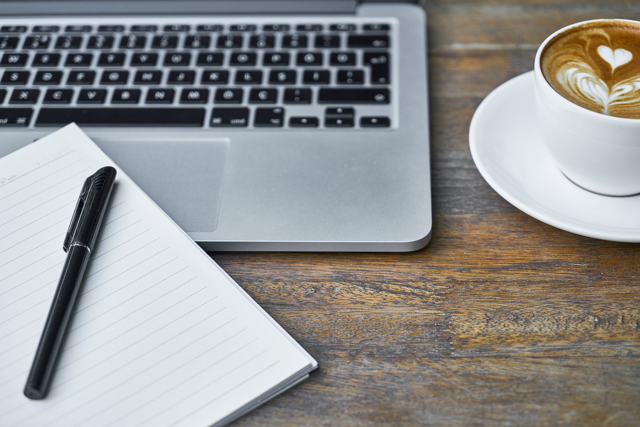 Computer keyboard coffee and a notebook
