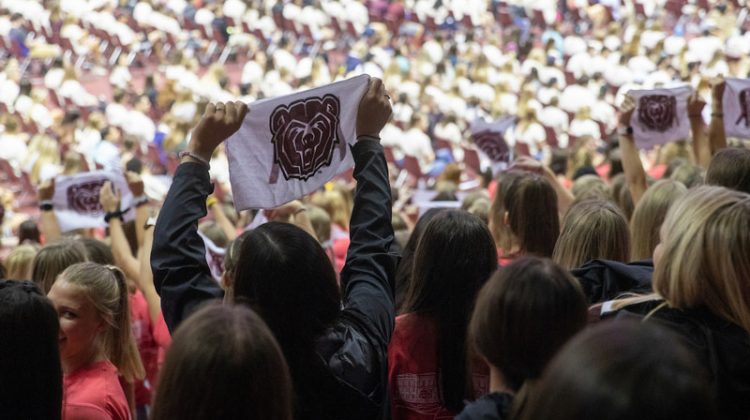 A student holds up a towel with the Missouri State bear head logo