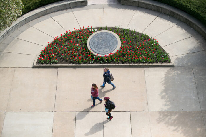 Students walking across campus with university seal