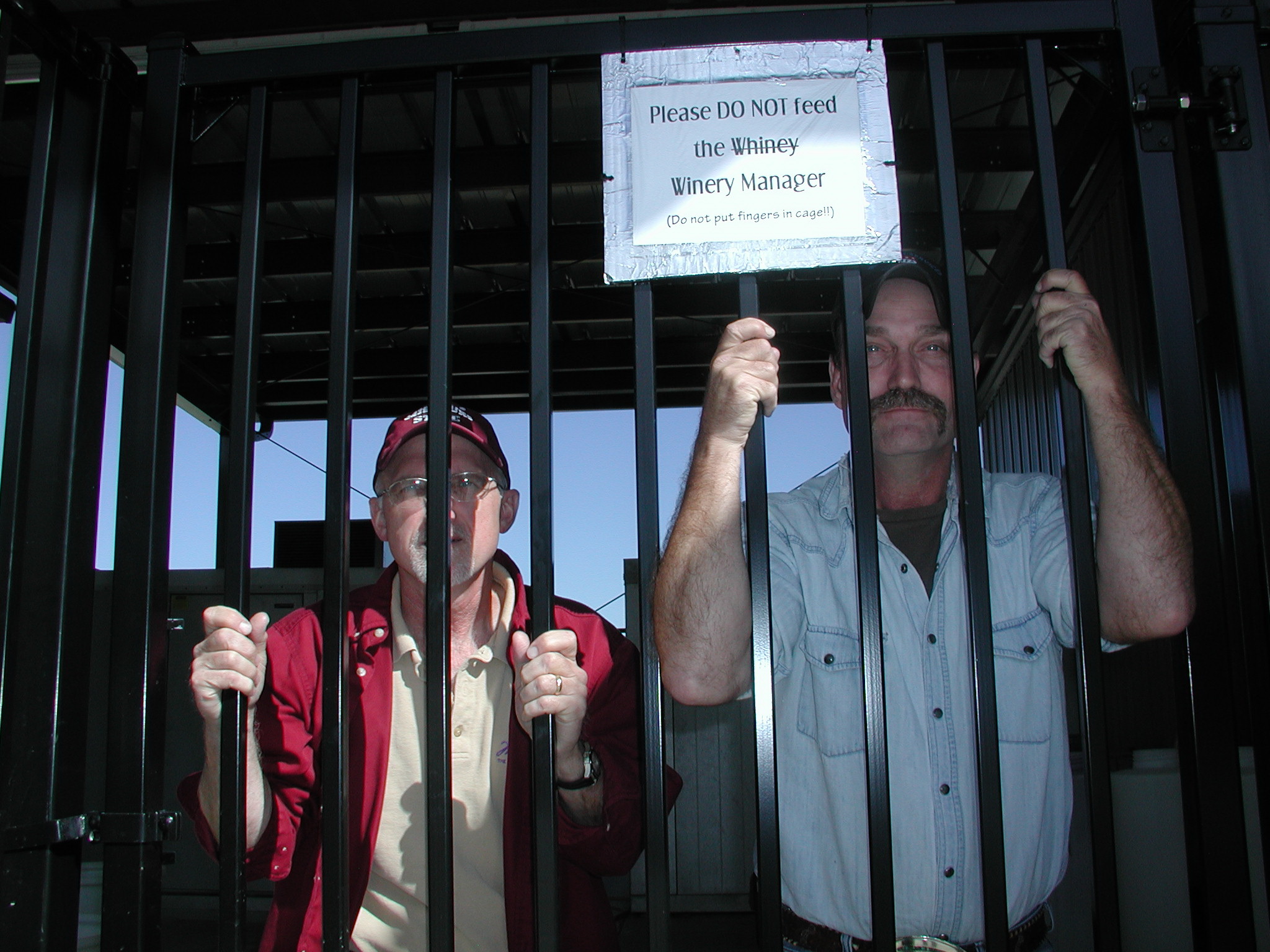 Dr. Karl Wilker (left) and C. J. Odneal (right) peer through the bars of the newly secured and covered outdoor wine processing area.