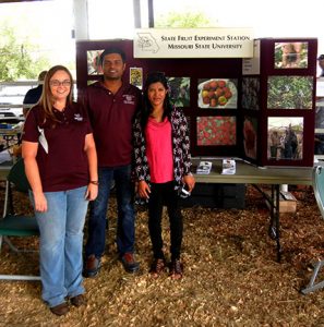 Jennifer Morganthaler, Surya Sapkota and his wife stand in front of our display.