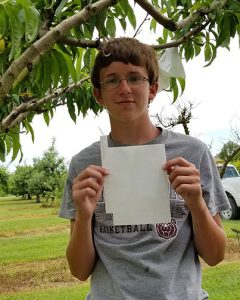 Anthony holds up one of the Clemson fruit bags. You can see the wired tab on the left. There are also vents on the bottom and a "V" notch at the top to fit around the branch.