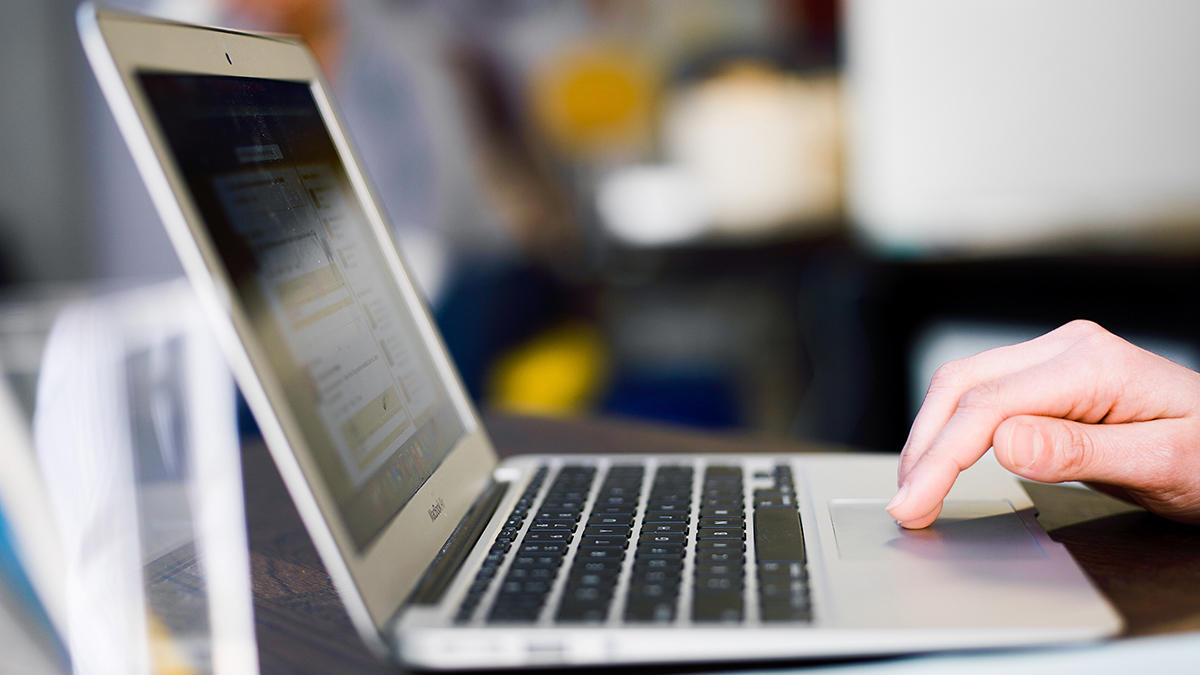 Sideview of hands setting on a laptop.