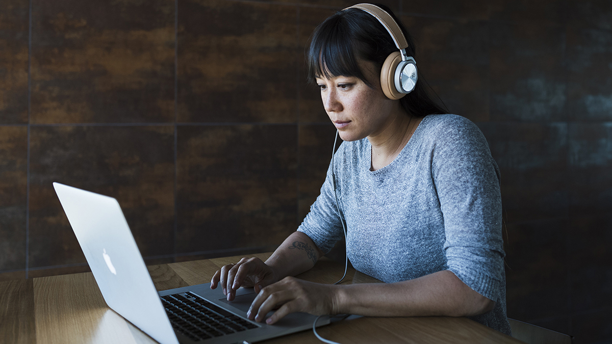 Woman at laptop wearing headphones.