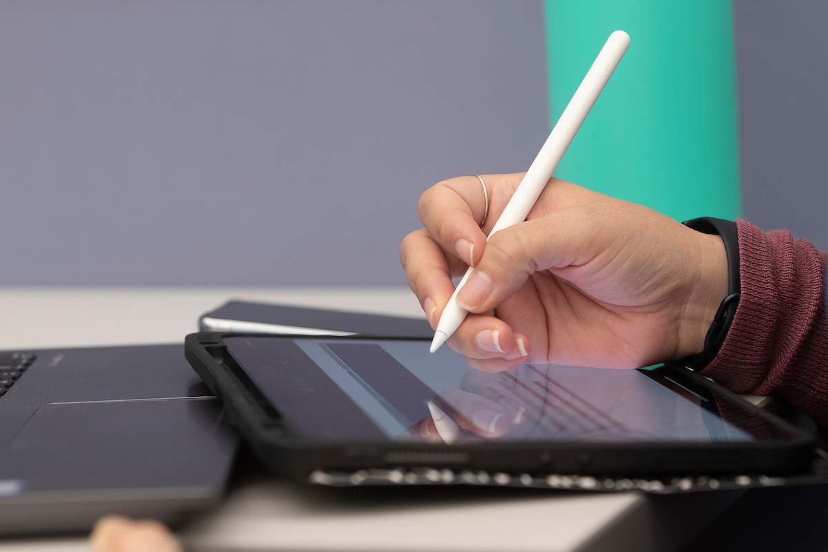 Hand holding stylus on tablet.