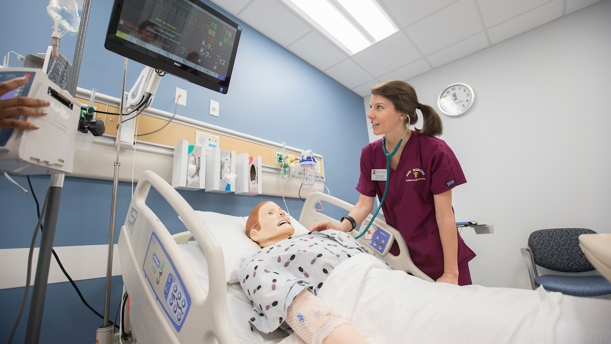 A nursing student attends to a simulated scenario