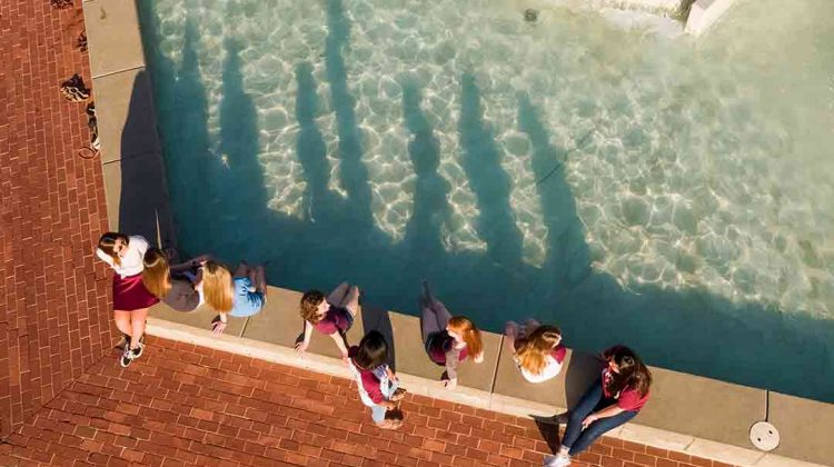 Aerial of students with feet in fountain