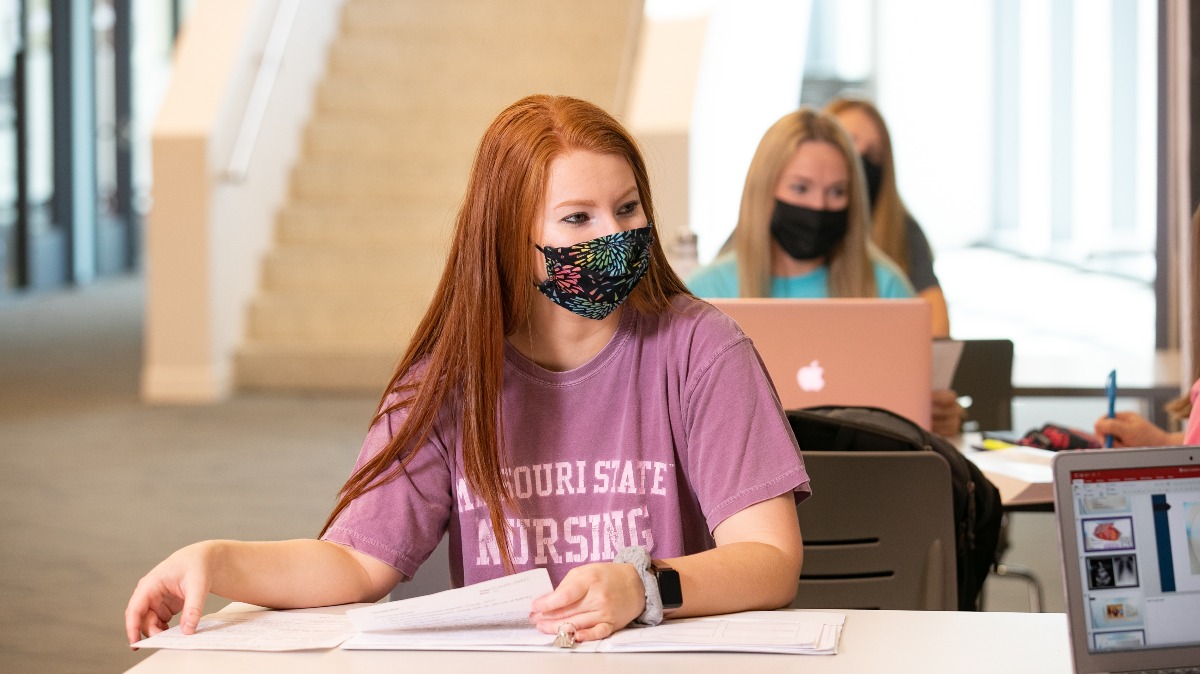Student studies while wearing mask.