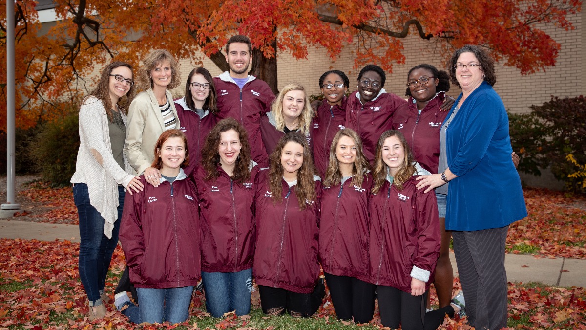 Glaessgen with 2018 Peer Leaders evening group in front of fall foliage.