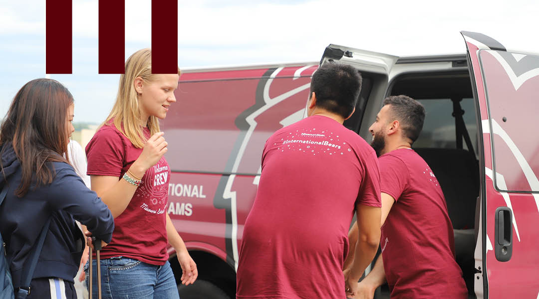 Staff help students load luggage into a Missouri State van