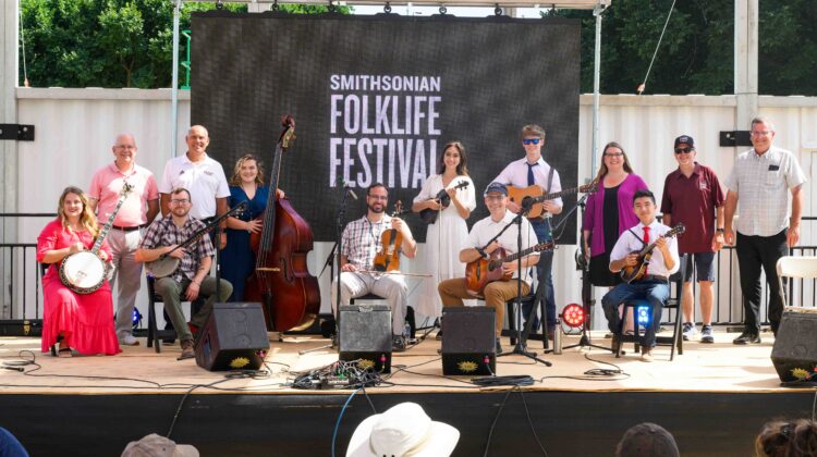 Ozarks musicians and MSU officials pose for a photo onstage at the 2022 Smithsonian Folklife Festival