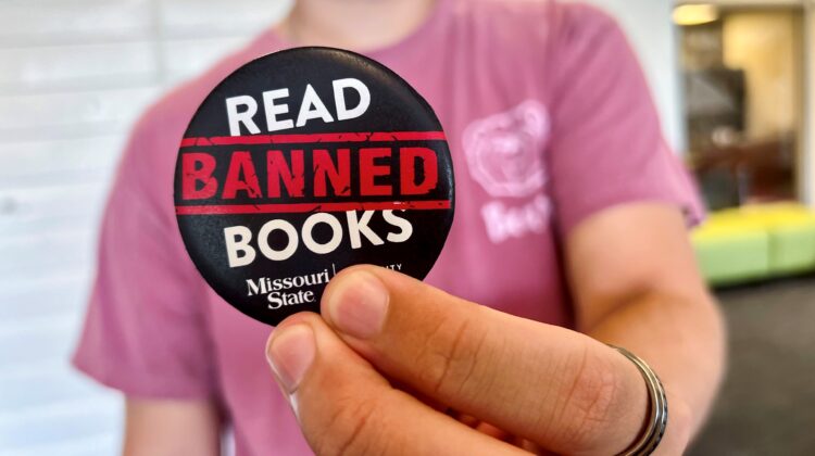 A student holds up a "Read Banned Books" button in Meyer Library