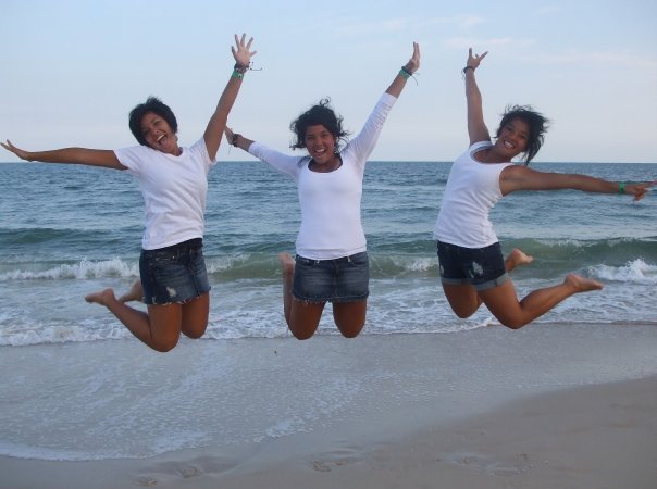 paige and her sisters jump in front of the ocean