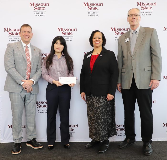 Dr. Gawon Yun smiling during her promotion celebration at Missouri State University, wearing professional attire and holding a recognition award or certificate.