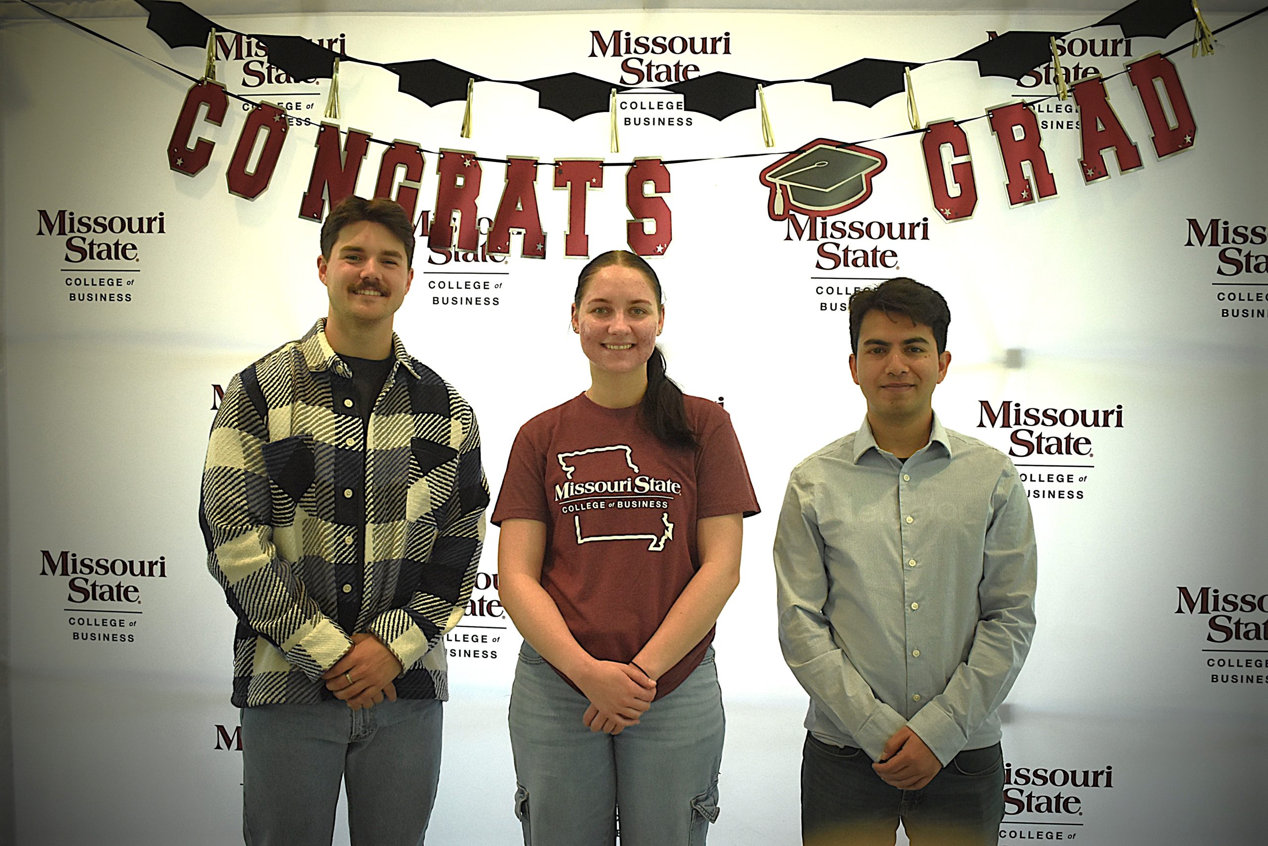 MSU Graduate Assistants Ethan D. Scott, Brenna Breitenstein, and Avas Basnet posing together after graduation at Missouri State University.
