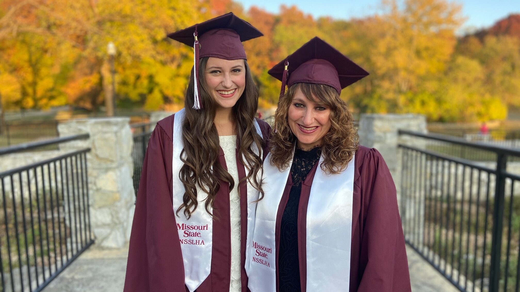 Two women standing in graduation cap and gown