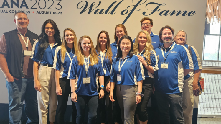 Members of the School of Anesthesia stand together in front of the AANA Wall of Fame