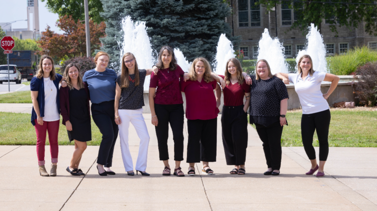 Advising team stands in front of fountain