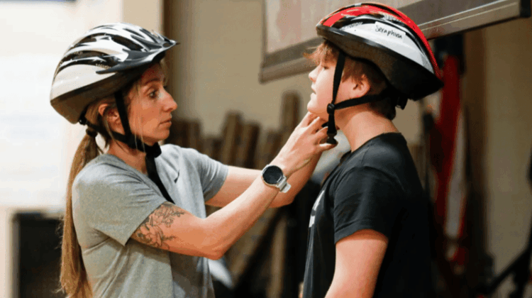 Danielle O’Neil helps a student get ready for PE with a helmet check.