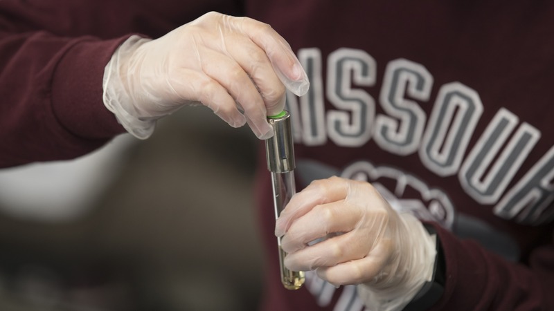 A Missouri State student holds a test tube.