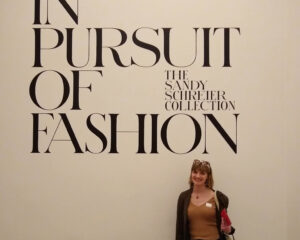 Girl in front of wall that reads, "In pursuit of fashion."