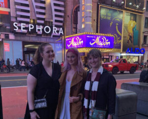 Three girls standing in front of a theatre.