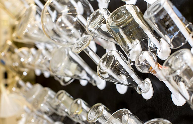 A collection of glass chemistry flasks hanging on a drying rack