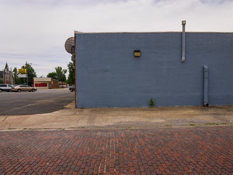 Building with blue exterior wall adjacent to brick pavers
