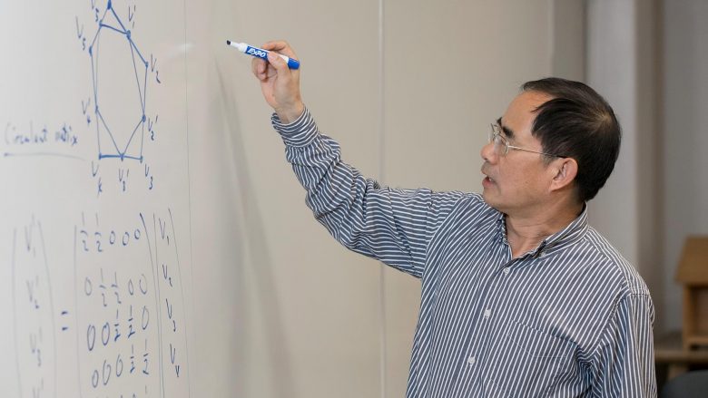 Dr. Xingping Sun writing an equation