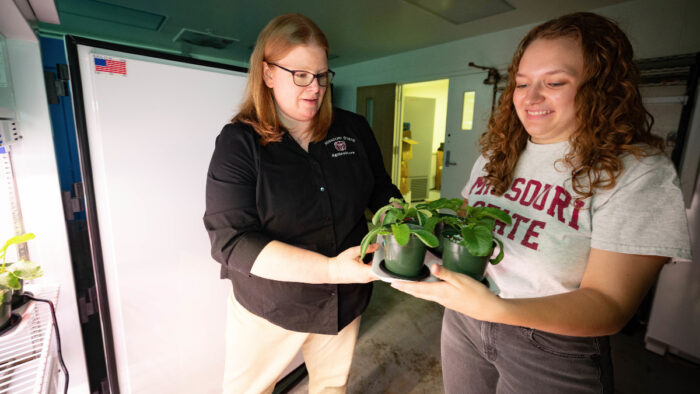 Melissa Bledsoe and student handle plants.
