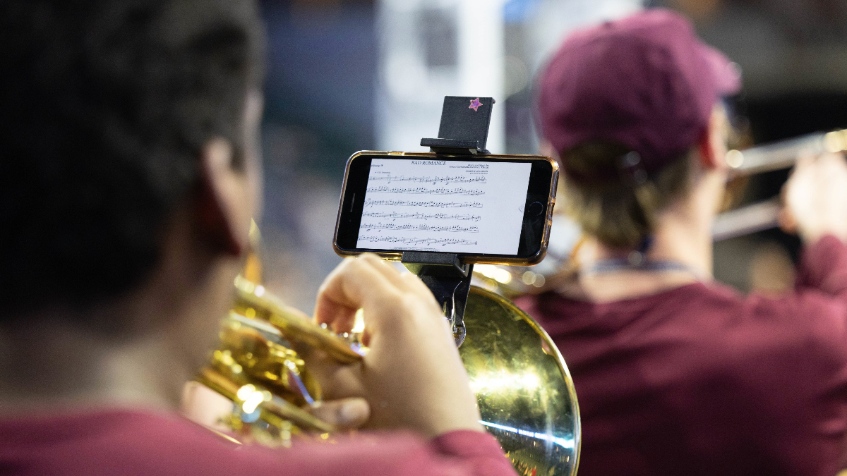 The back of a trumpeter's head while displaying the phone that has music and plans.