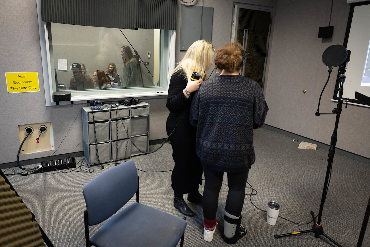 Sharon Kenny and a vocal student rehearse while a team of students led by Christina Pippa listen from inside the audio booth. 
