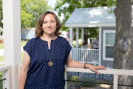 Dr. Marnie Watson smiles from the front porch of a tiny home at Eden Village.