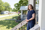 Dr. Marnie Watson leans against a porch rail of a tiny home at Eden Village.