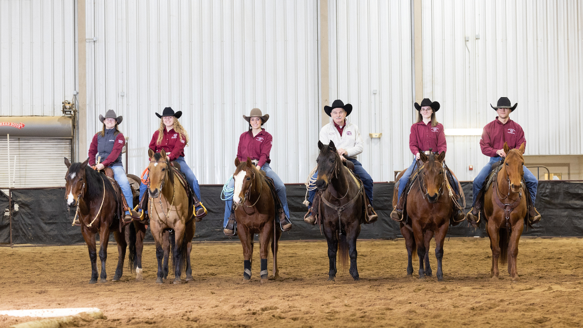 Gary Webb and five students pose on horseback in arena.