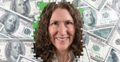 Dr. Adams peers through a hole in a money-themed jigsaw puzzle.
