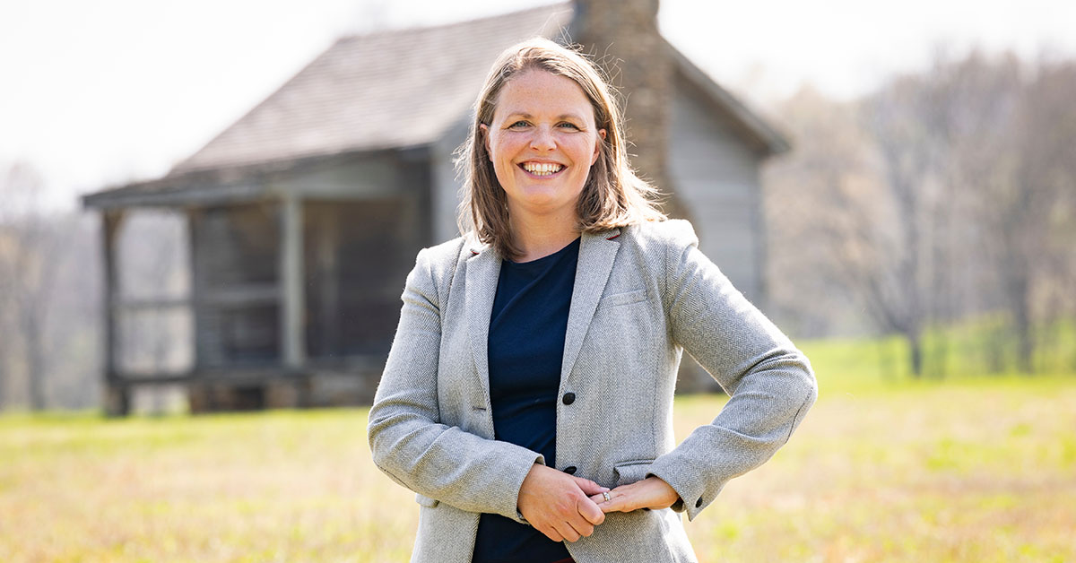 Dr. Philippa Koch poses in front of a farmhouse.