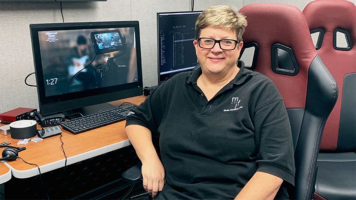 Dr. Deborah Larson seated at an editing bay in Strong Hall control room.