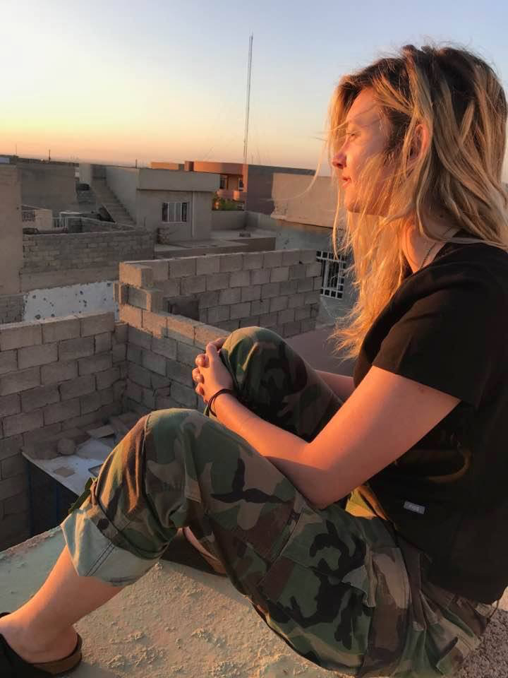 Madeline sitting on a rooftop during a sunset